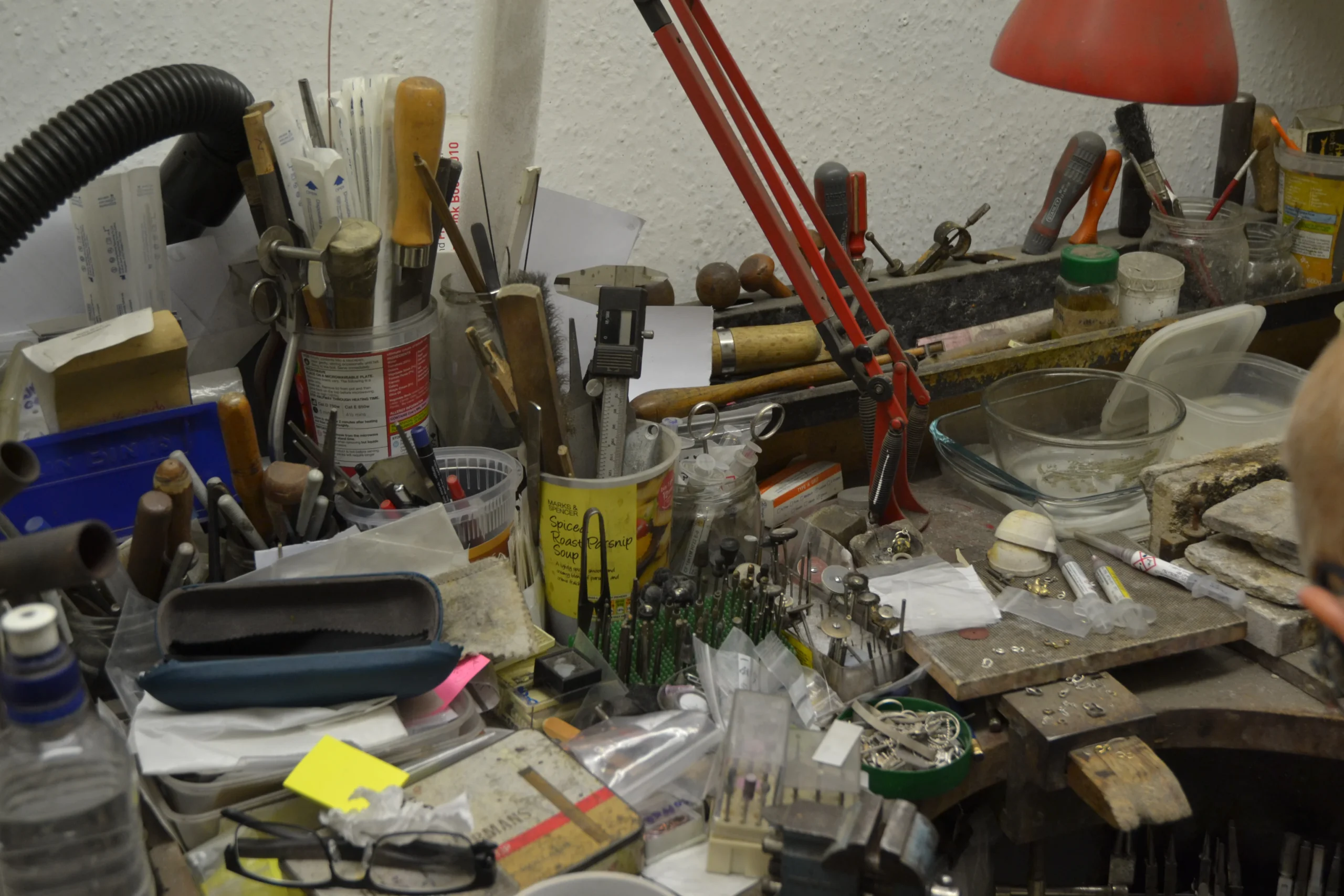 Close-up of a traditional jeweller's workbench filled with specialist hand tools and equipment used for professional jewellery repairs at Alexander Jewellery Chichester.